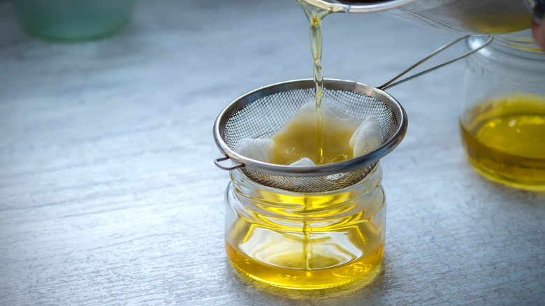 Fat being strained through cheesecloth into jar