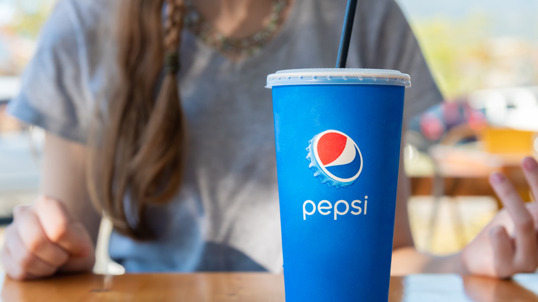 Woman sitting with disposable soda cup