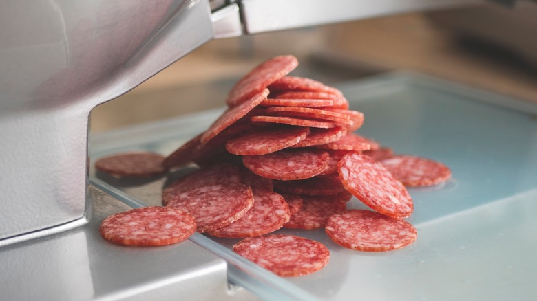 pepperoni slices on a metal slicing machine