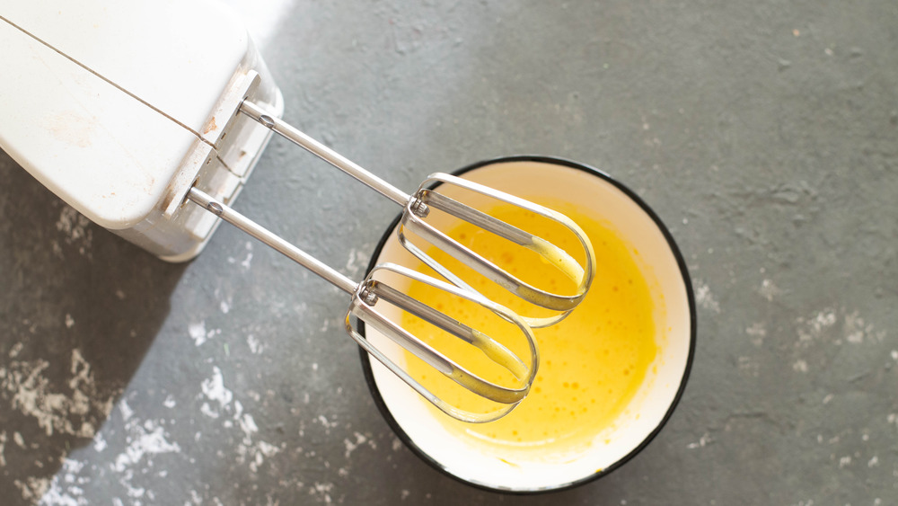 Egg beaters over a bowl of beaten eggs