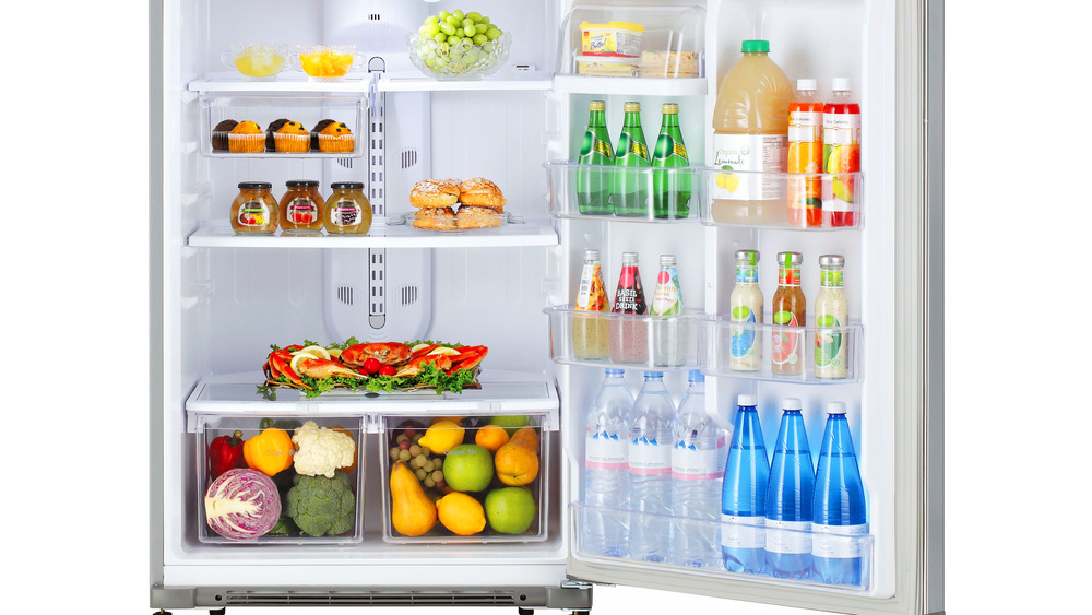 open fridge with fruits, vegetables, muffins, juice, sparkling water, and cheese