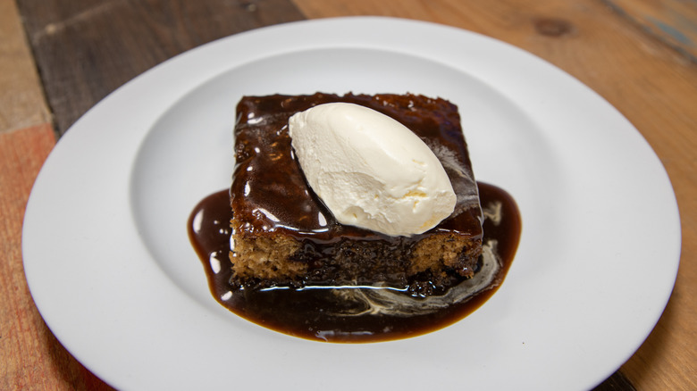 Sticky toffee pudding with cream on a white plate