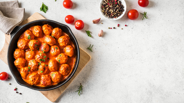 cast iron pan of meatballs on a wooden serving board