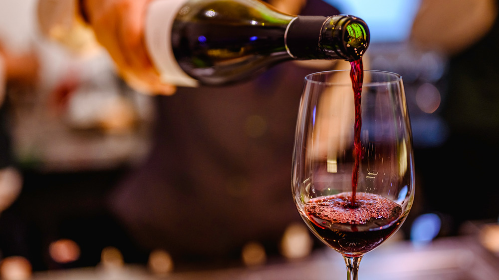 Hand pouring red wine into glass