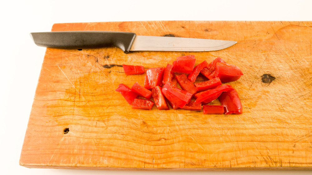 Knife with sliced peppers on cutting board