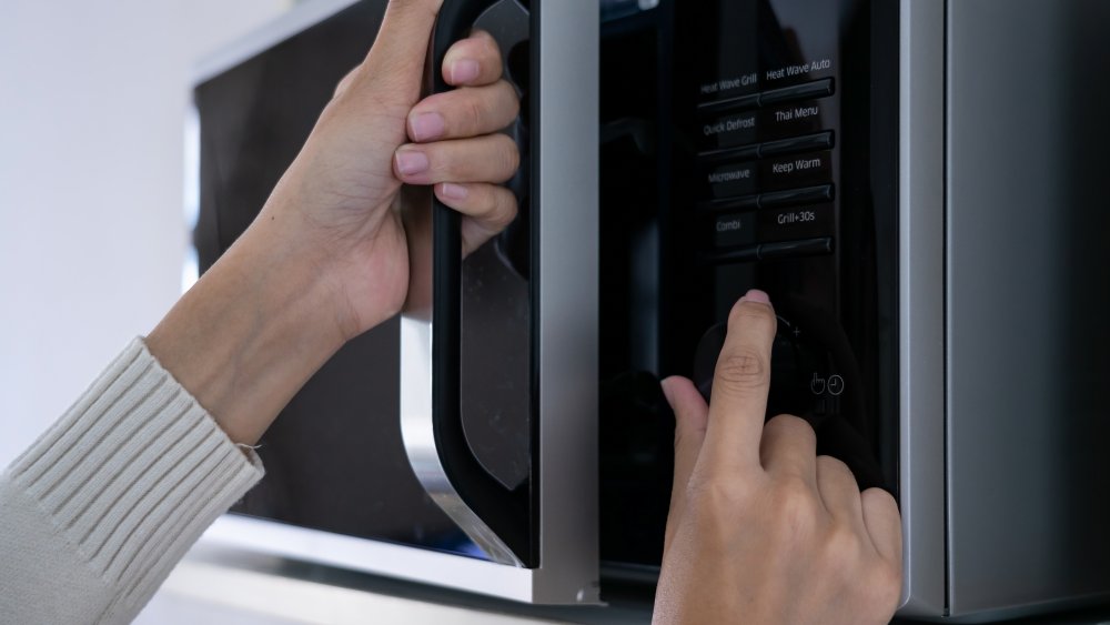 Woman inputting time on a microwave