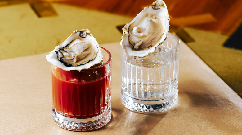 two oysters on top of vodka shot glasses