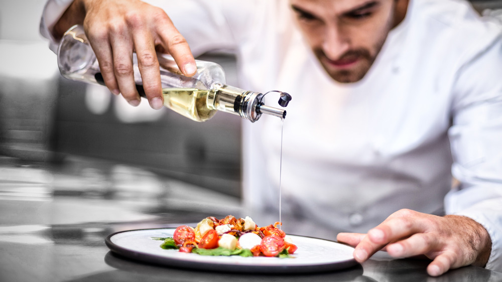 Chef pouring finishing oil onto a meal