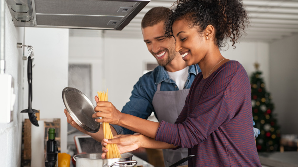 A couple cooking pasta together