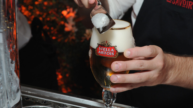 Stella Artois in a chalice with foam being sliced off