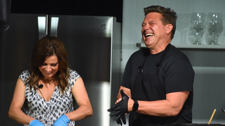 Tyler Florence smiling in a cooking demo with Martina McBride