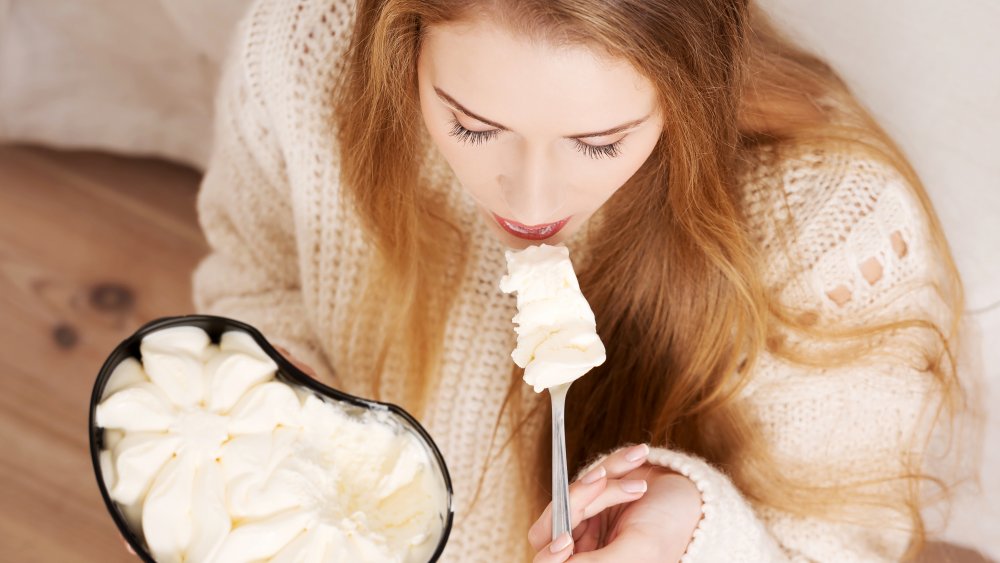 Woman eating bowl of ice cream in fall sweater