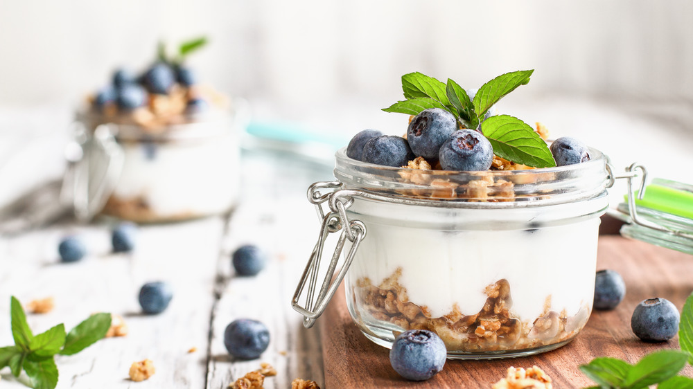 Mason jar filled with yogurt, blueberries, and granola