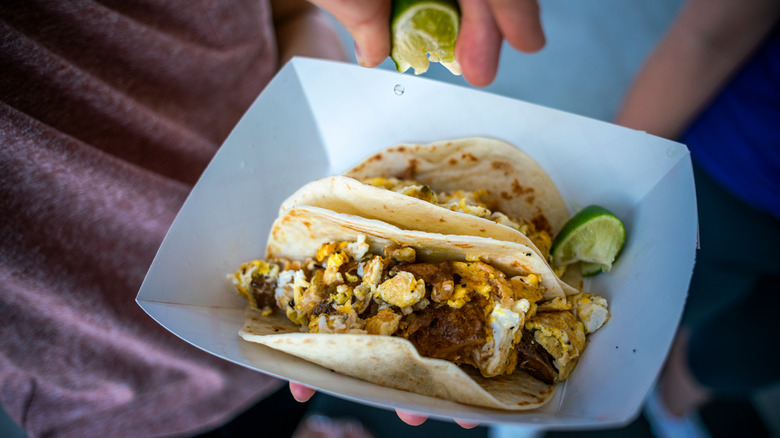 Person squeezing lime over tacos