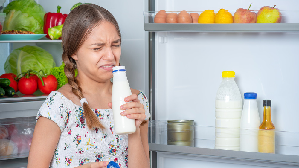 Girl sniffing spoiled milk