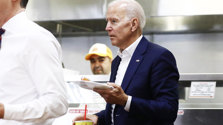 President Biden holding food and drink in a restaurant kitchen