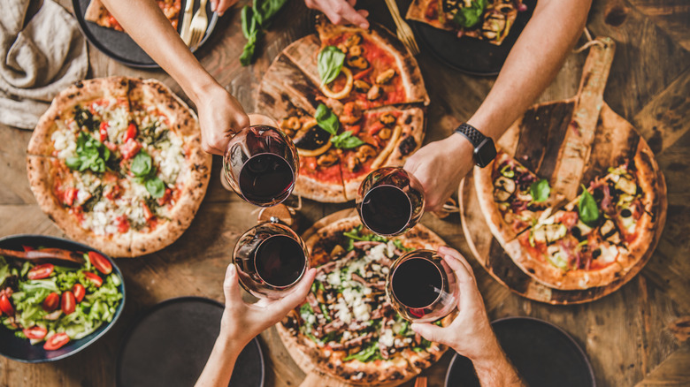 Hands holding wine glasses over table of food