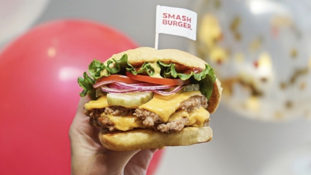 Hand holding up cheeseburger with tiny Smashburger flag