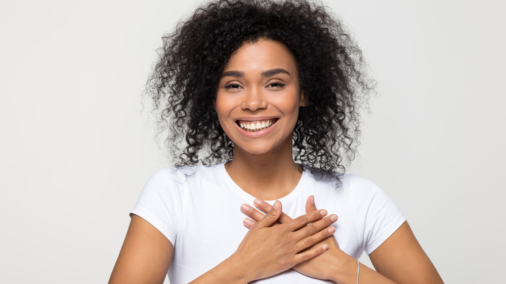 woman signaling hand over heart and smiling