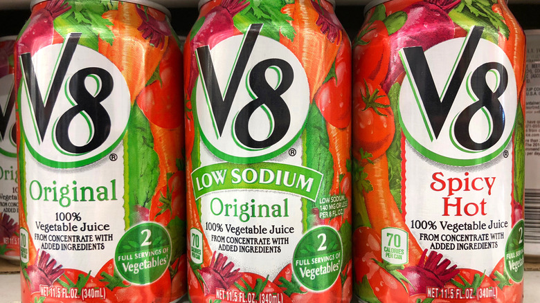 Three V8 vegetable juice cans in Original, low sodium Original, and Spicy varieties