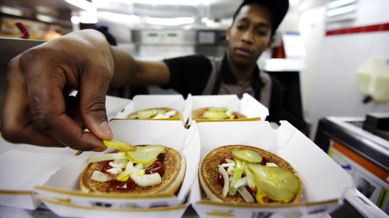 McDonald's worker putting pickles on bun