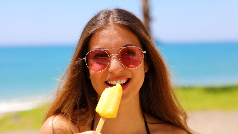 Girl in sunglasses eating popsicle