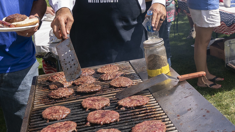 People grilling burgers on a black grill