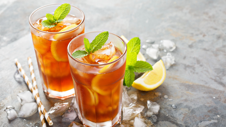 two glasses of iced tea with lemon wedges and paper straws