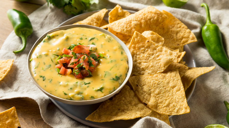 A white bowl of queso and tortilla chips