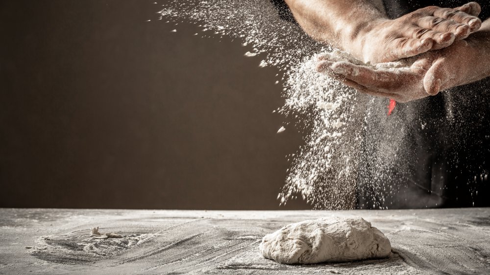 Man hands making pizza dough with flour