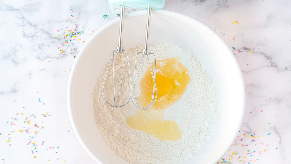 mixing in an egg to rainbow cake mix