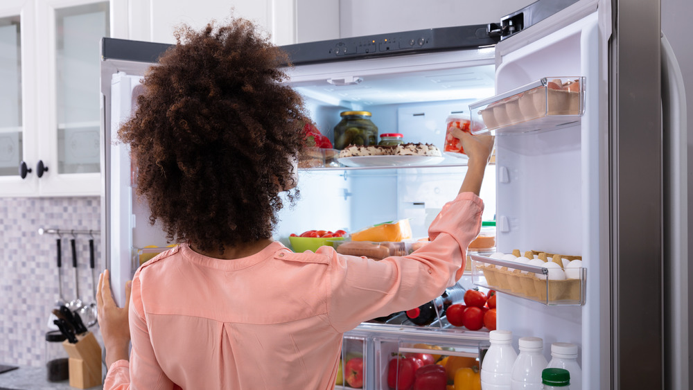 Woman looking at leftovers in her fridge