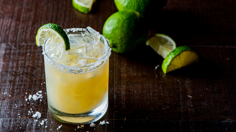 Margarita made with orange juice in a cocktail glass with salted rim and limes in the background