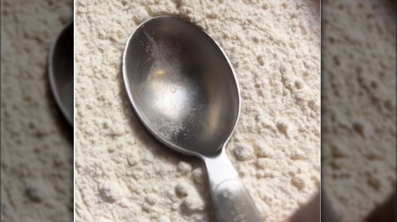 measuring spoon pressed against flour 