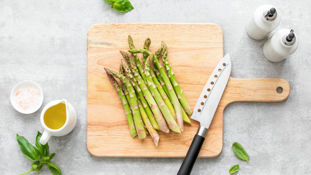 asparagus on wooden cutting board with knife