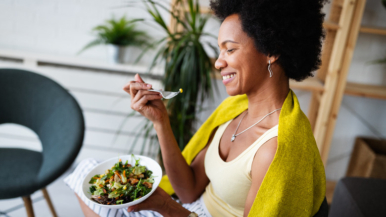 Woman smiles while eating salad