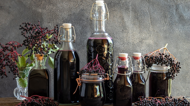 Syrup, wine, jam in jars surrounded with elderberries