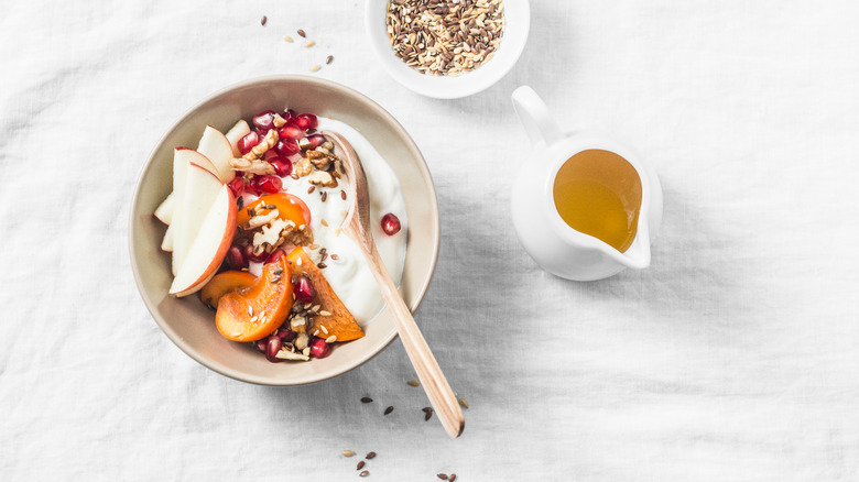 yogurt bowl with persimmons, sliced apples, pomegranate seeds