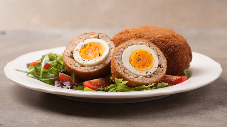 Scotch eggs on white plate with mixed salad