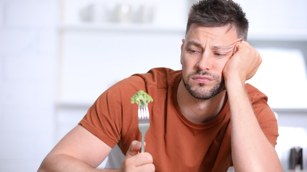 Man looking displeased by broccoli