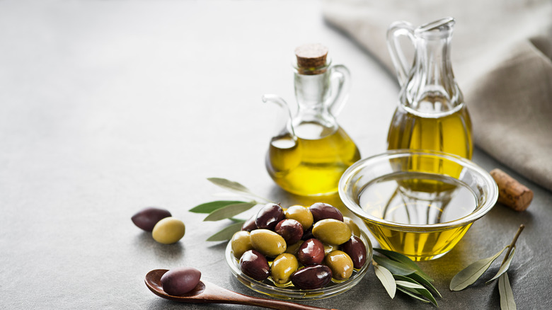 Bowl and two jars of extra virgin olive oil next to a bowl of olives