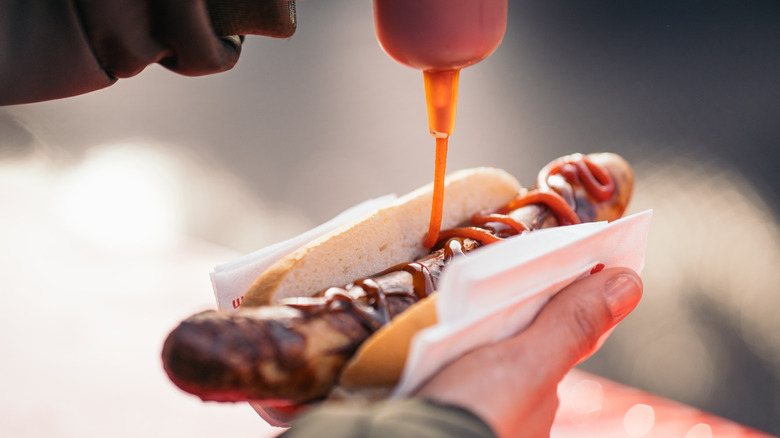 drizzling ketchup on hot dog