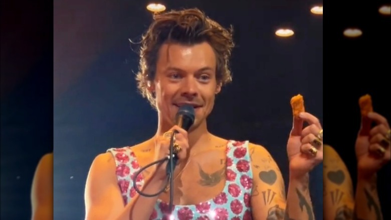 Harry Styles holding a chicken nugget onstage 