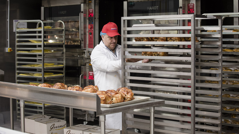 Costco employee placing rotisserie chickens on rack