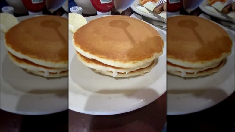 A pancake on a plate, with a spoon above it