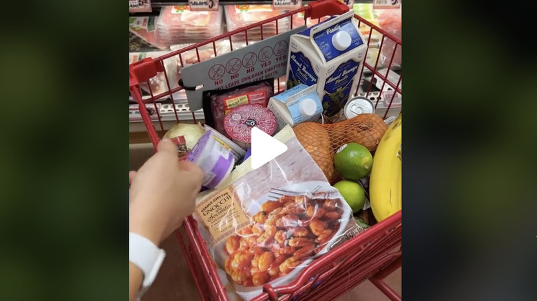 shopper throwing groceries in full Trader Joe's cart