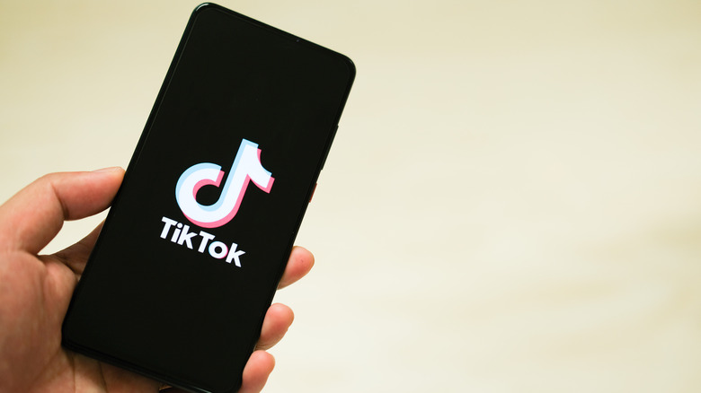 Person holding a phone with the TikTok logo