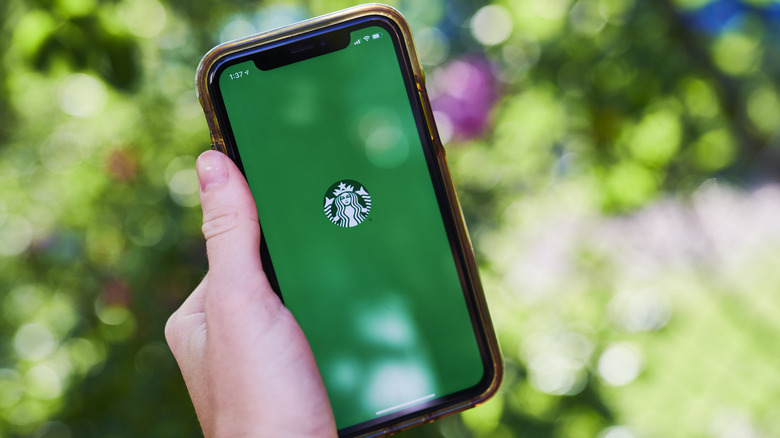 Person holding phone with Starbucks app