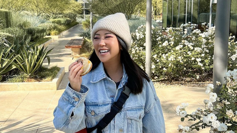 Ashley Yi smiling outside holding a sandwich 