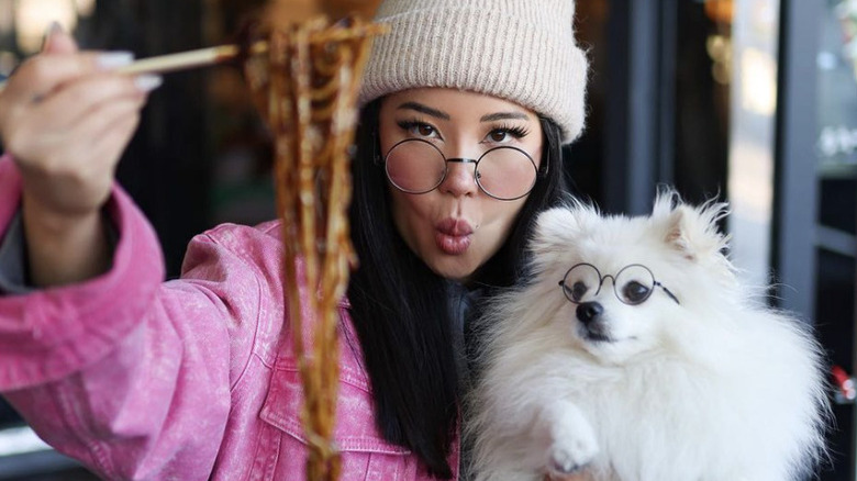 Ashley Yi posing with chopsticks and dog